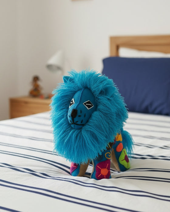 A handmade Mexican-style felted wool llama doll with a vibrant blue shaggy mane, decorated with colorful floral patterns on its body and brown felted wool legs, set against a plain white background.